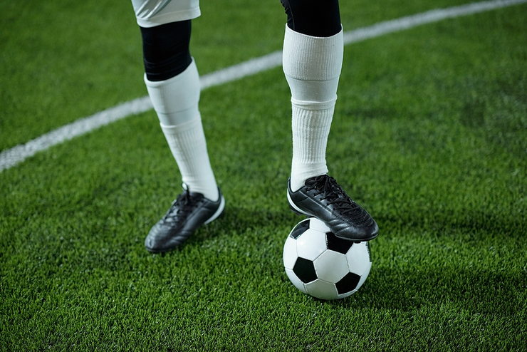 Legs of Footballer Standing on Ball